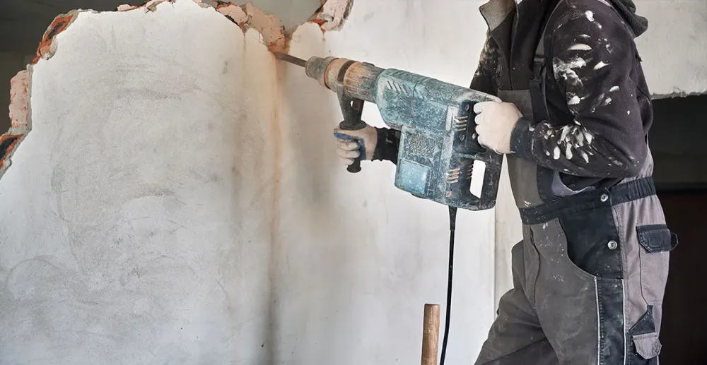 demolition-Homme-qui-utilise-une-perçeuse-à-percussion-pour-creuser-dans-un-muwebp