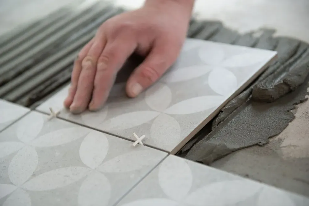 Focus-sur-une-main-qui-pose-des-carreaux-de-carrelage-avec-des-motifs-1400w